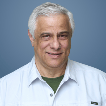 Dr. Dimitrios Diamandidis is smiling in a professional headshot with a white button down shirt against a blue background