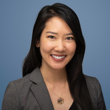 Kimberly Ho is smiling for a professional headshot wearing a necklace and gray blazer