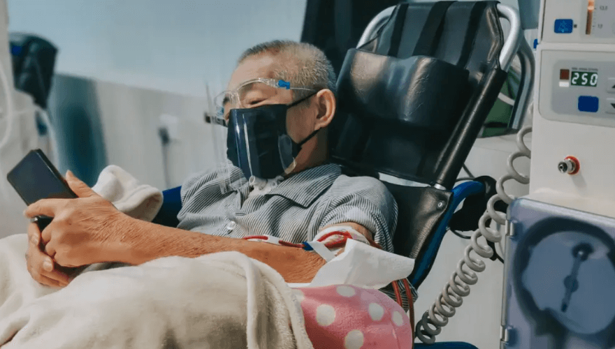 Man in hospital bed looks at phone
