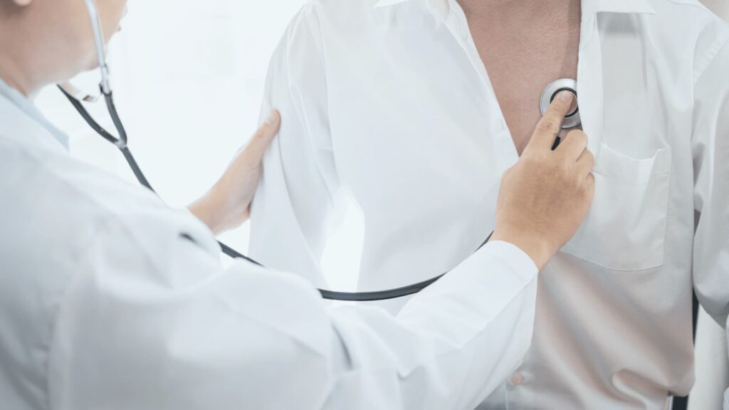 Medical examination with stethoscope against patient's chest checking lungs