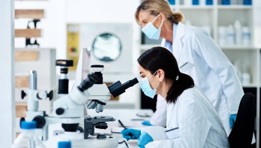 Women in clinical research lab looking into microscope